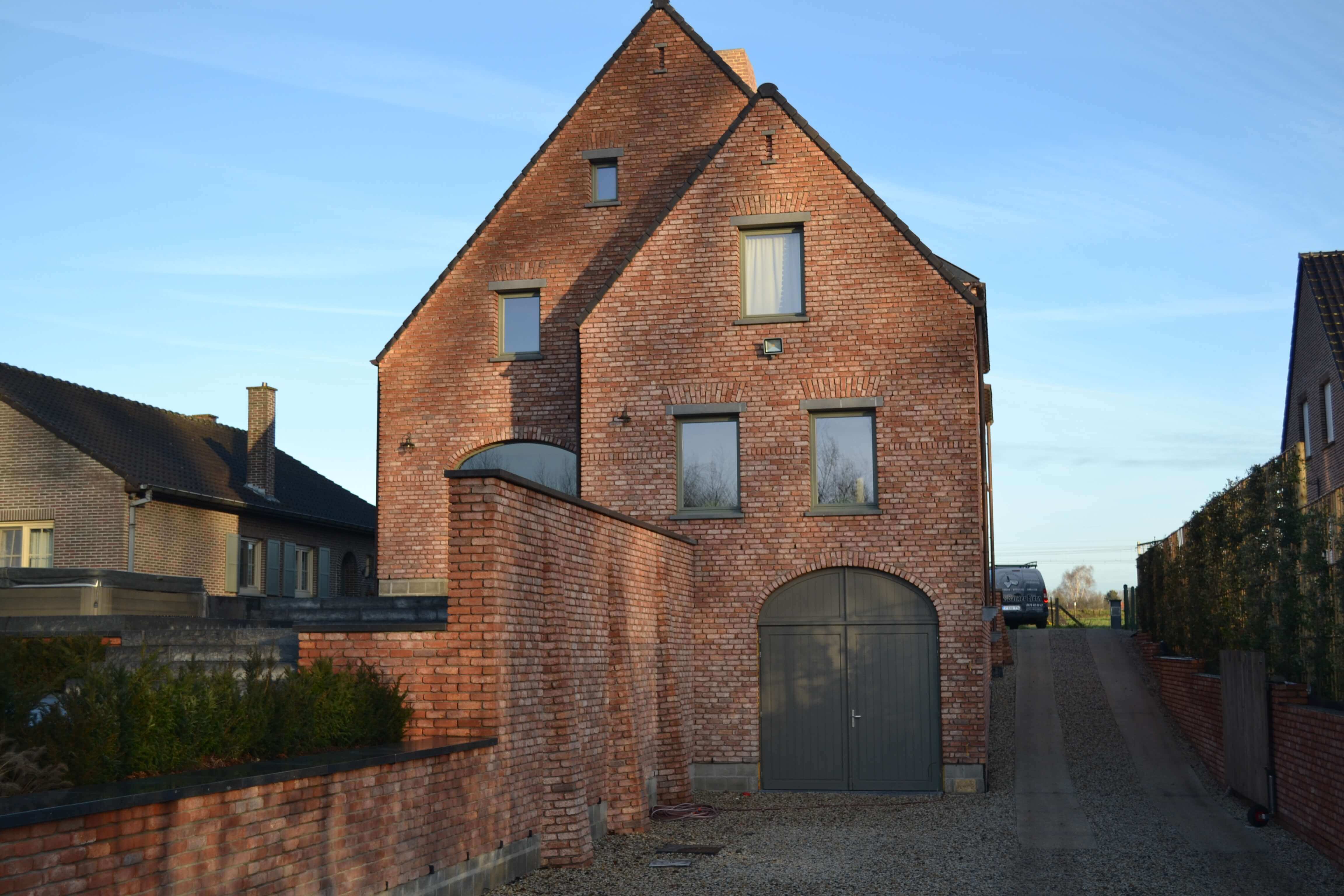 achterzijde nieuwbouw met oprit gewassen beton en zijmuur met siermetselwerk