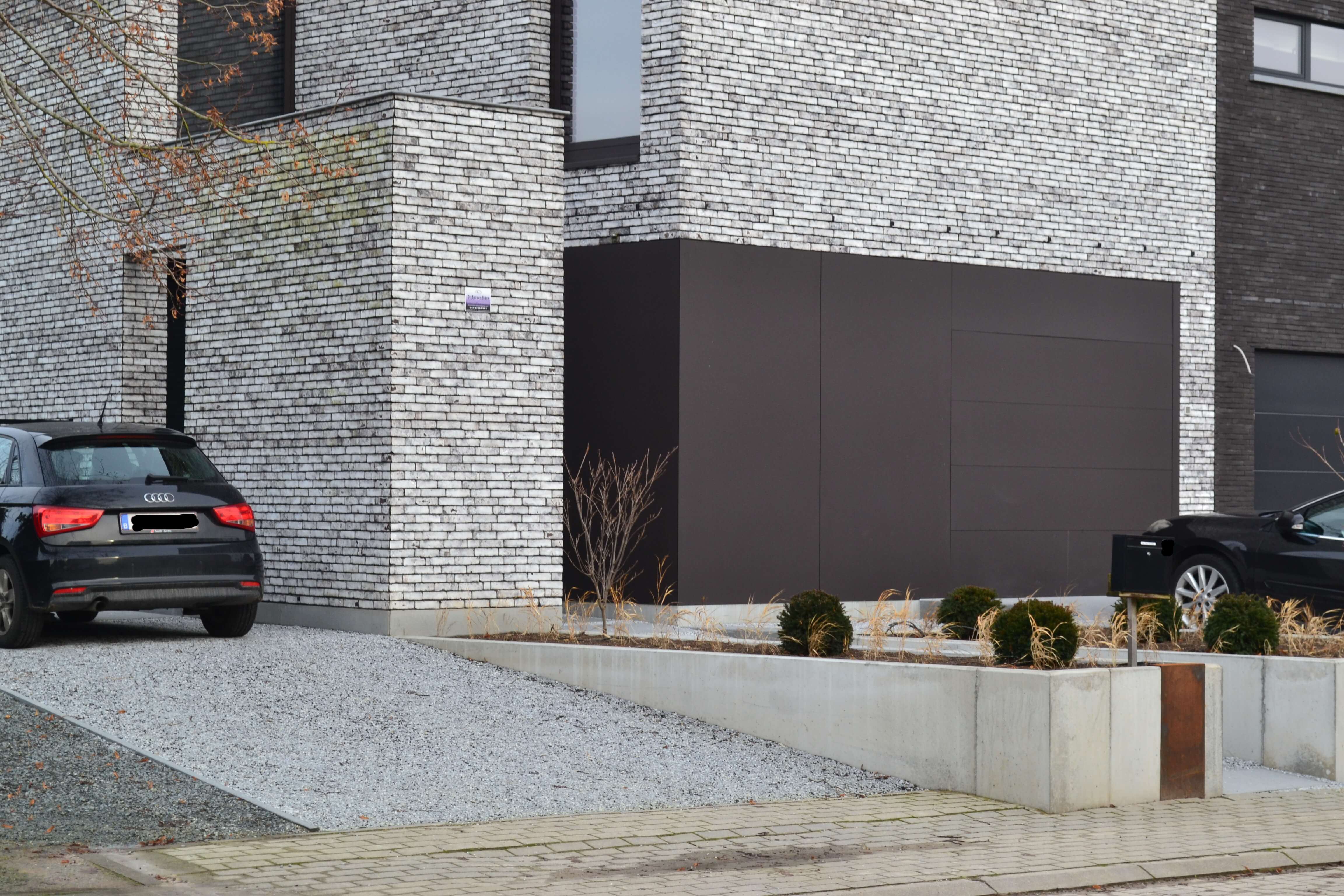 bruine garagepoort en lichtgrijze moderne gevelsteen