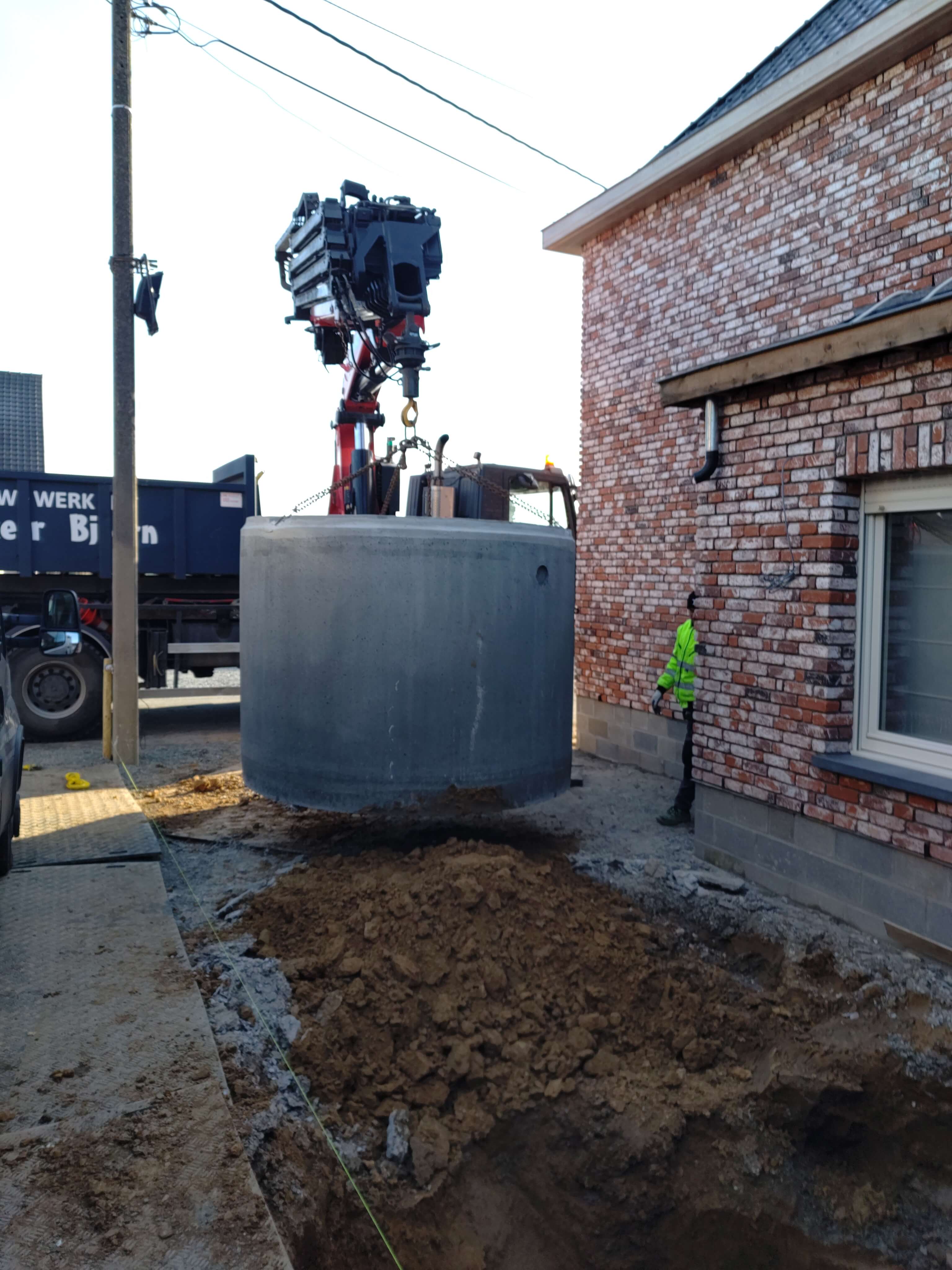 Graafwerken met kraan voor plaatsen van regenwaterput tijdens Verbouwing